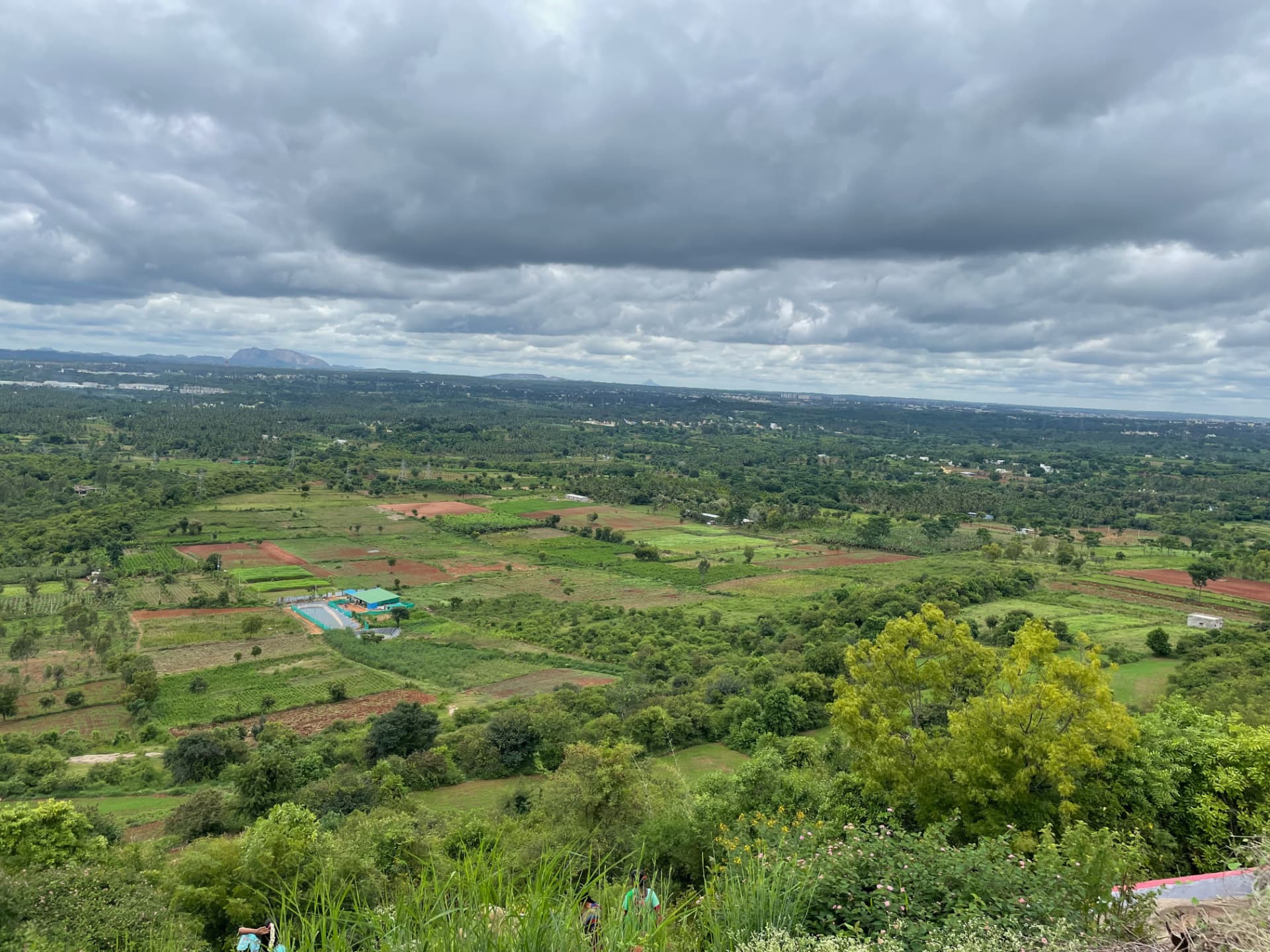 Aerial view of green farmland and hills near Bidadi under monsoon clouds